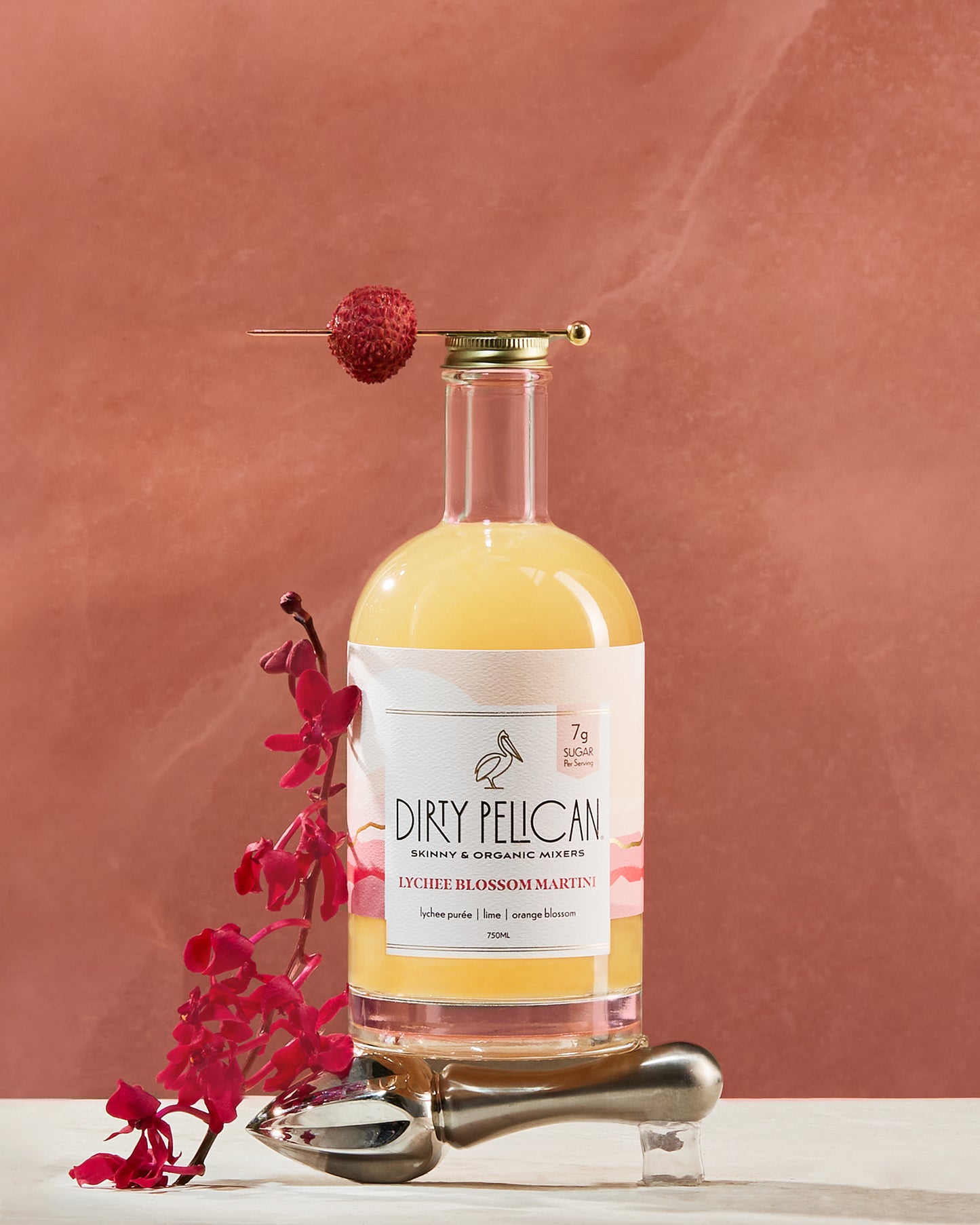 Bottle of Dirty Pelican mixer with a pink flower on a brown background