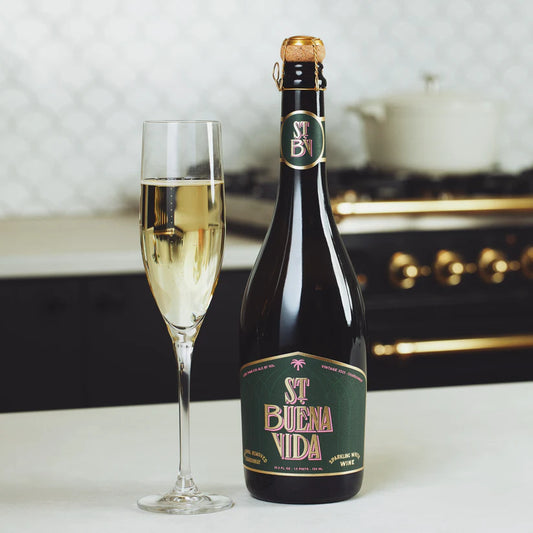 Bottle of St. Buena Vida wine with a glass of champagne on a kitchen counter.