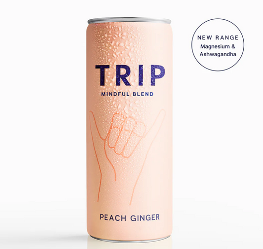 A can of TRIP Mindful Blend Peach Ginger Sparkling Botanical Drink with a pink hue and hand graphics, indicating a new range with magnesium and ashwagandha.