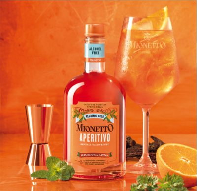 A bottle of Mionetto Aperitivo Spritz Mixer with a glass of the cocktail garnished with an orange slice, a copper jigger, and fresh mint leaves in the foreground.