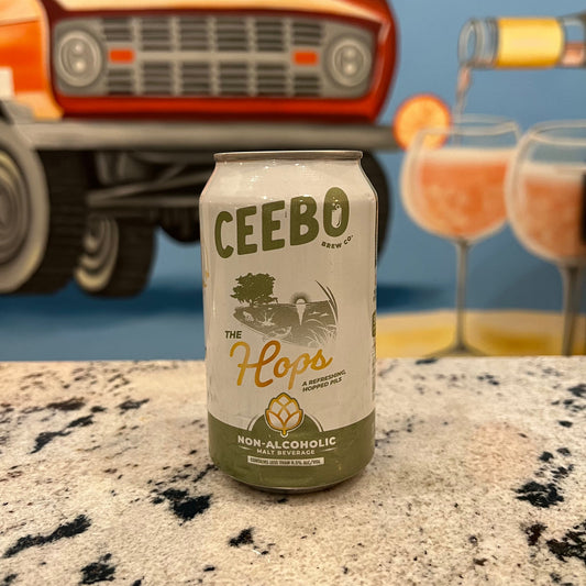 Ceebo non-alcoholic beer can on a textured surface with a vintage truck and cocktails in the background.