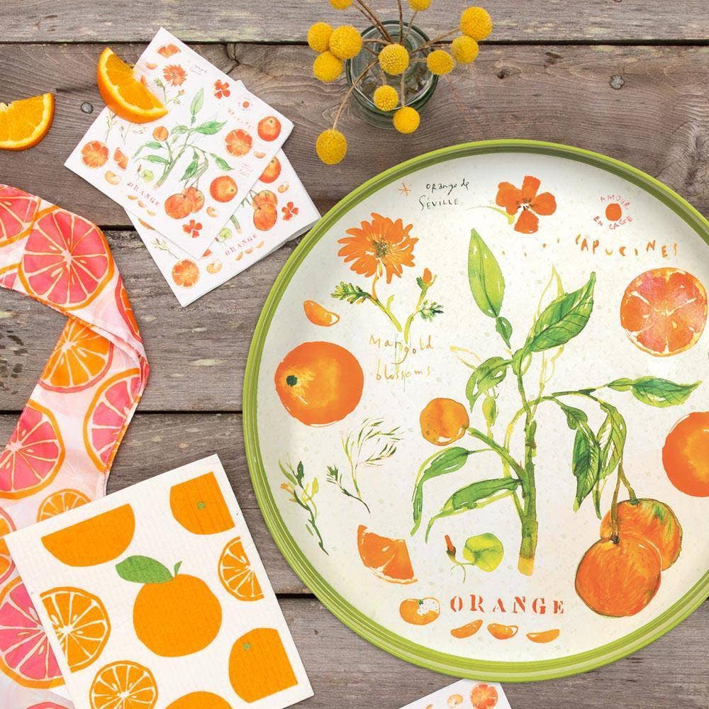 Decorative plate with orange illustrations on a wooden surface with matching products.