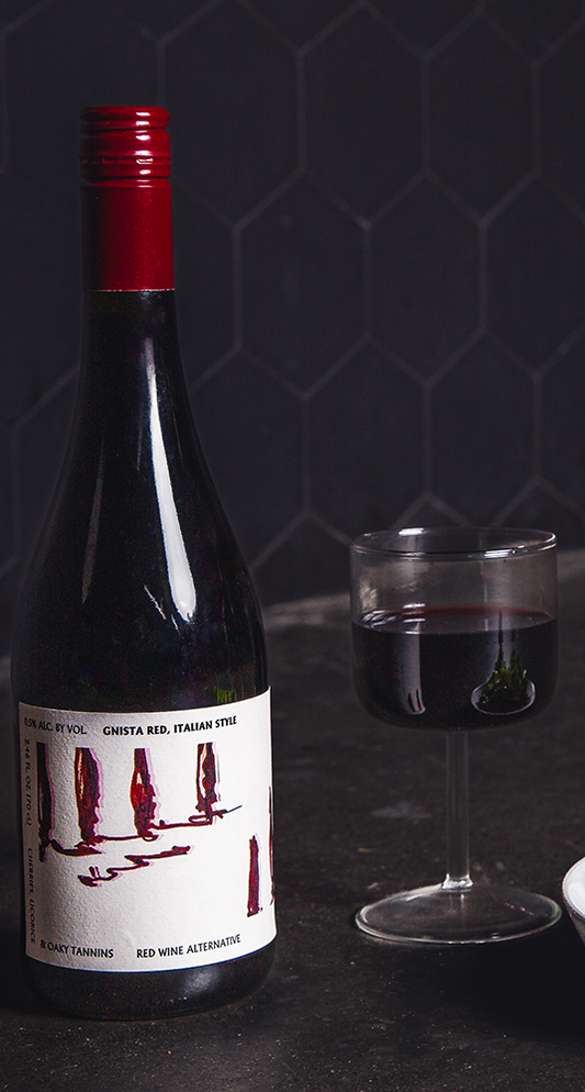 Bottle of red wine with a glass on a dark surface