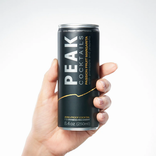 A hand holding a can of Peak Cocktails Passion Fruit Margarita.
