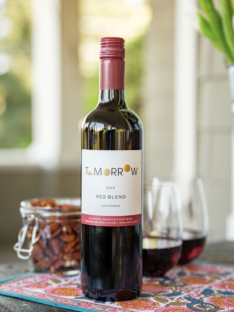 Bottle of Tomorow Red Blend wine on a table with glasses and snacks.