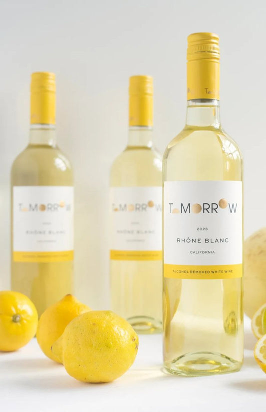 Three bottles of 'Tomorrow' white wine with lemons on a light background