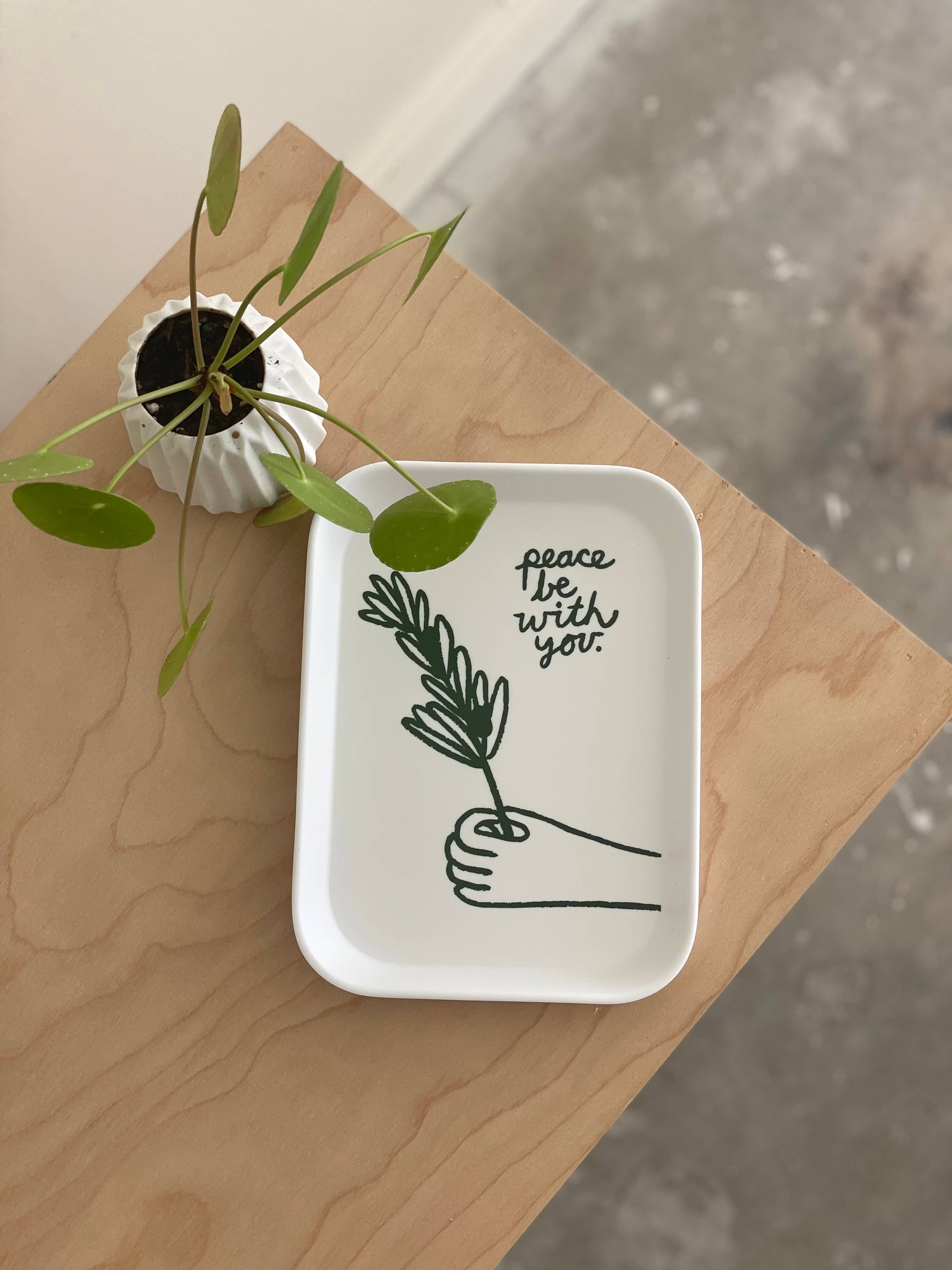 White ceramic tray with plant design and text on a wooden surface