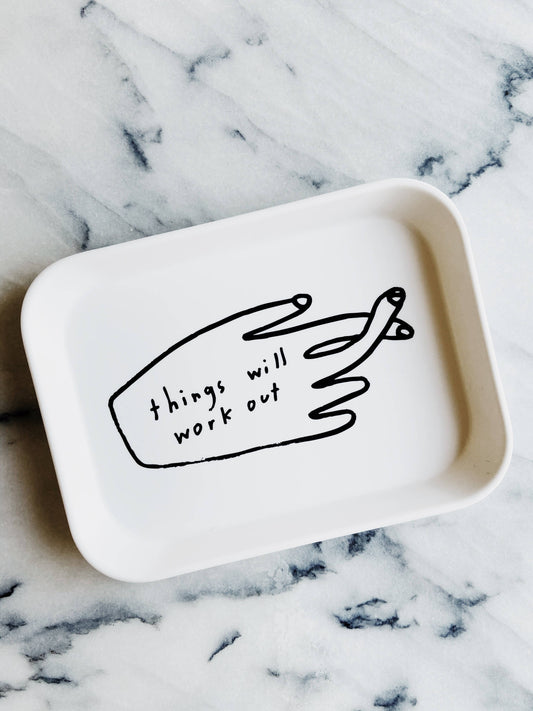 White tray with a black hand-drawn illustration and text 'things will work out' on a marble surface