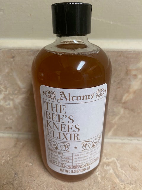 Bottle of 'The Bee's Knees Elixir' with a label on a tiled surface