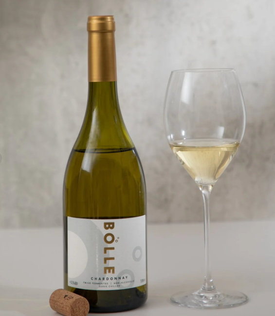 A bottle of Bolle Chardonnay non-alcoholic wine accompanied by an empty wine glass, displayed against a neutral background.