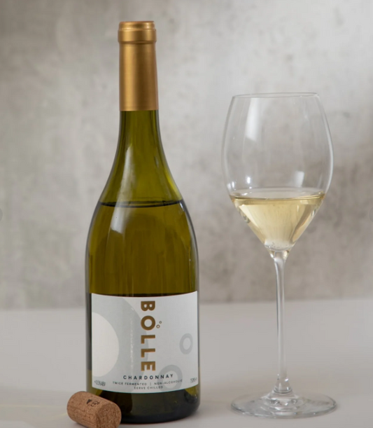 A bottle of Bolle Chardonnay non-alcoholic wine accompanied by an empty wine glass, displayed against a neutral background.