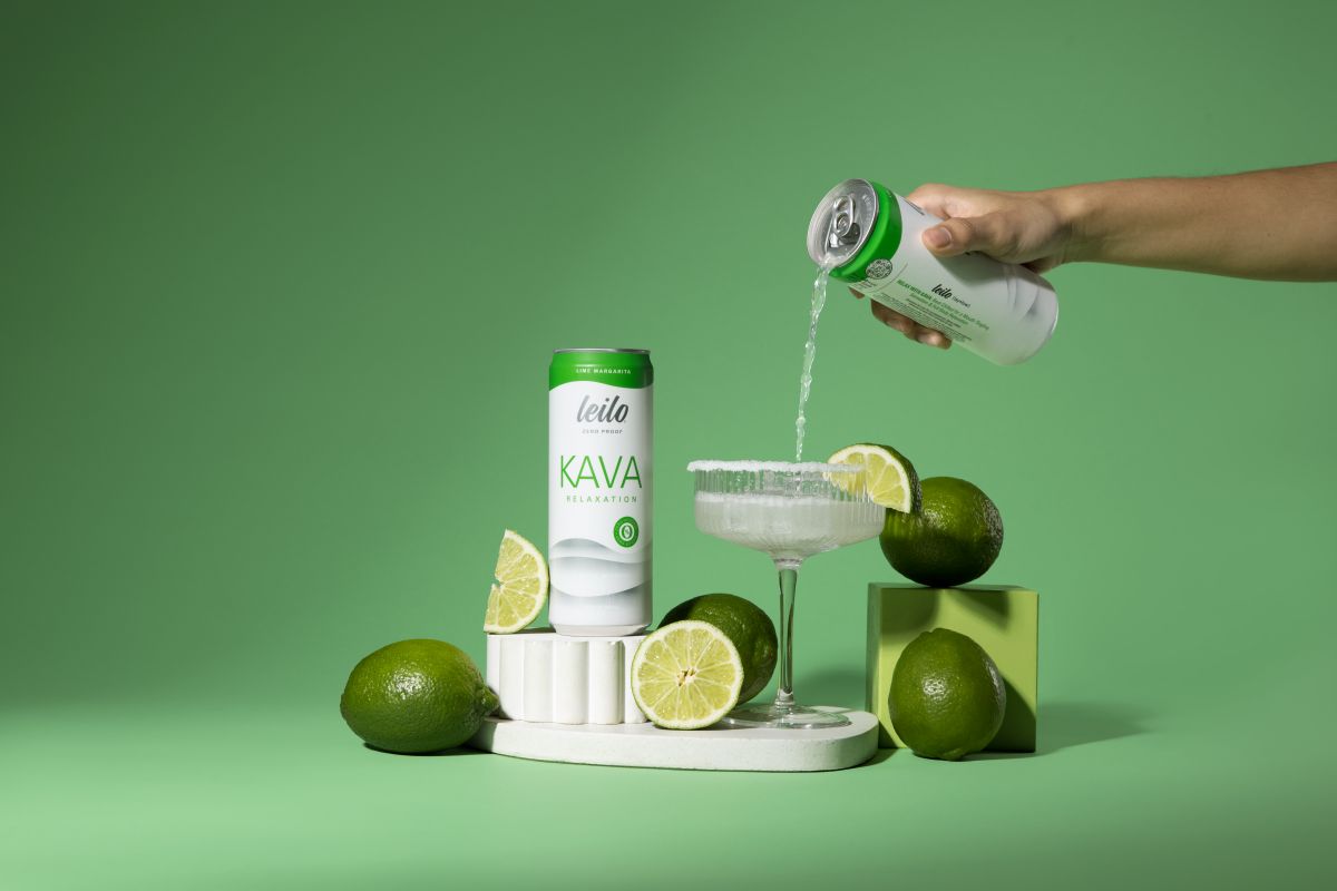 Person pouring Kava powder into a glass with lime slices on a green background