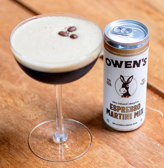 Glass of Espresso Martini with a can of Owen's Espresso Martini Mix on a wooden surface