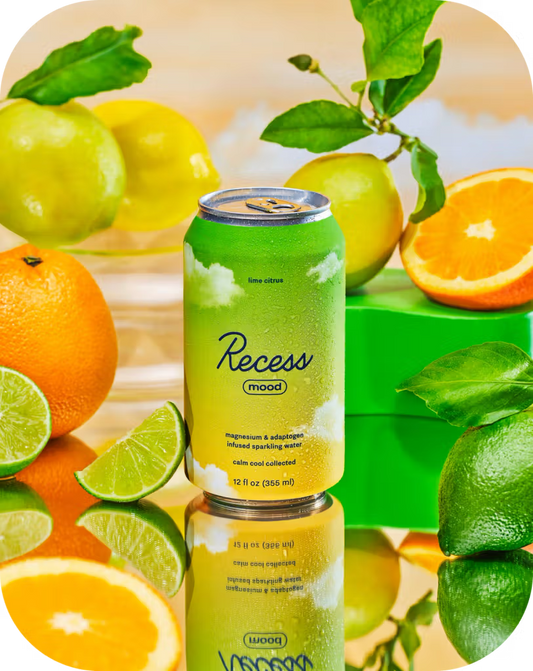 Green can of Recess mood surrounded by citrus fruits on a reflective surface
