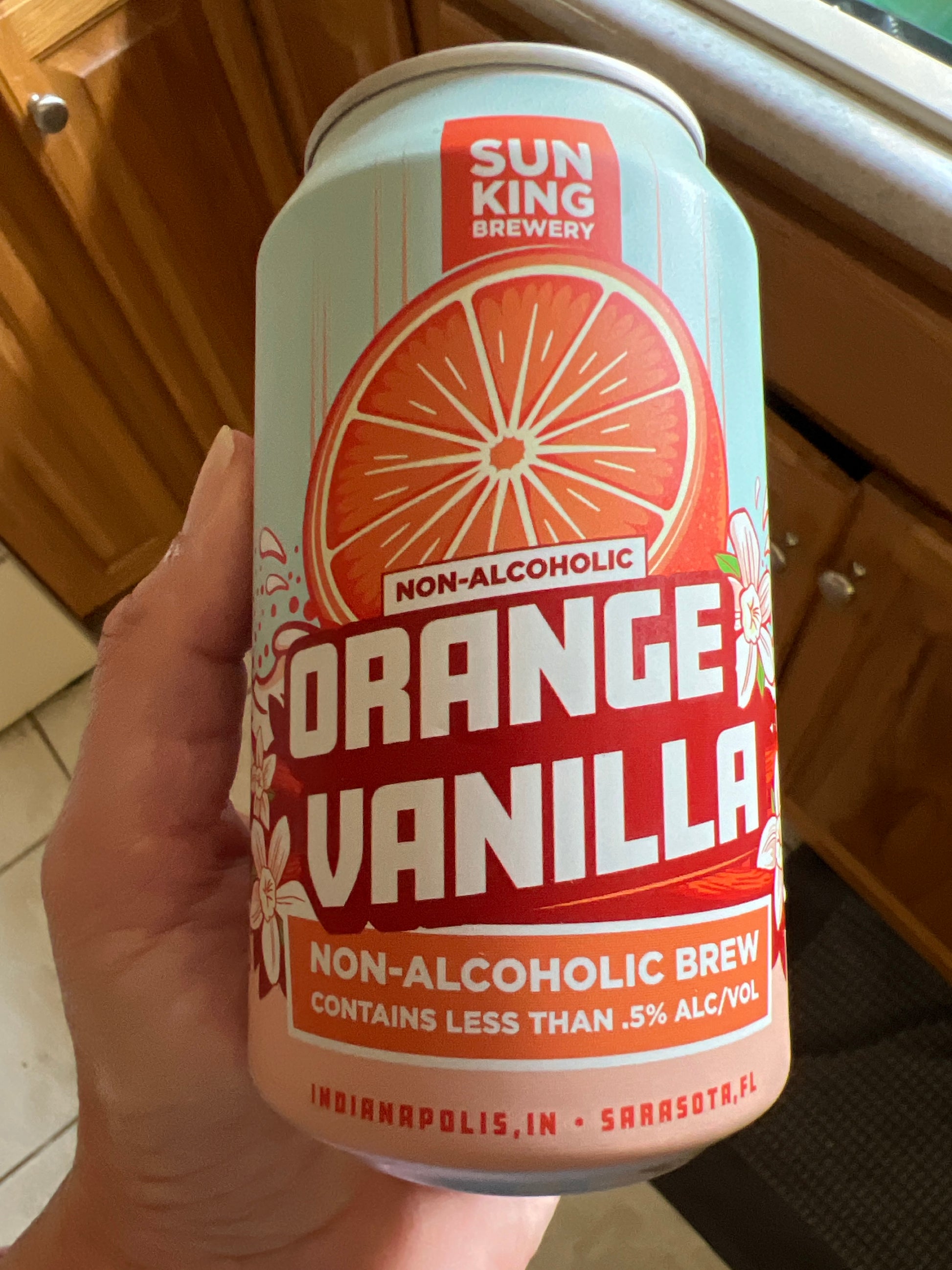 Hand holding a can of Sun King Brewery Orange Vanilla non-alcoholic brew.