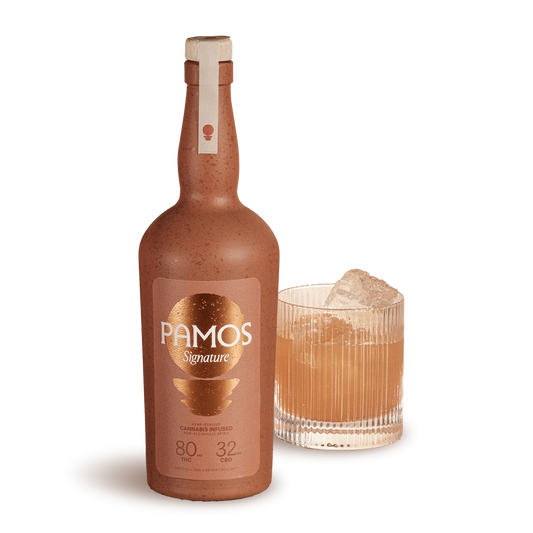 Pamos bottle with a glass of amber-colored liquid on a white background